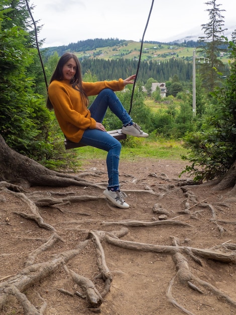 Mujer viajera disfrutando de columpiarse en columpio y vista a la montaña