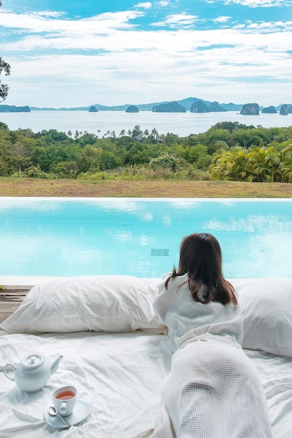 Mujer viajera feliz disfruta de la hermosa vista al mar Turista relajante en un complejo tropical de lujo con piscina Viajes de ocio y concepto de vacaciones de verano