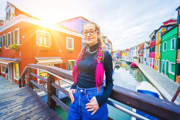 Mujer viajera feliz divirtiéndose cerca de casas coloridas en la isla de burano en la laguna veneciana viajes y