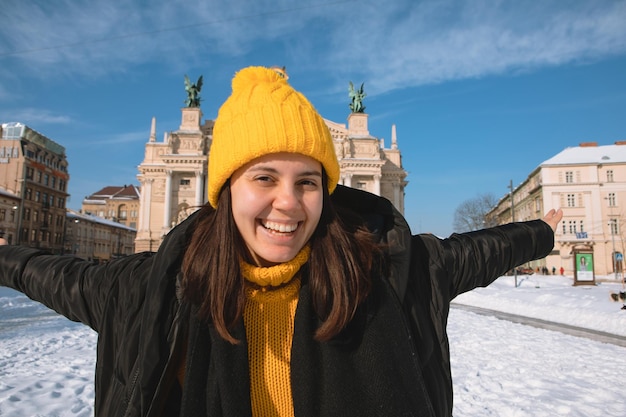 Mujer viajera feliz frente al edificio de la ópera en la ciudad de lviv