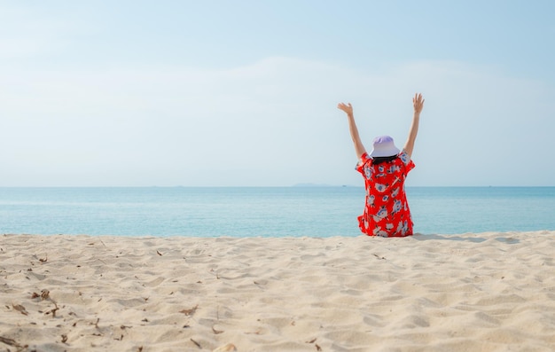 Mujer viajera feliz con vestido rojo disfruta de sus vacaciones en la playa tropical