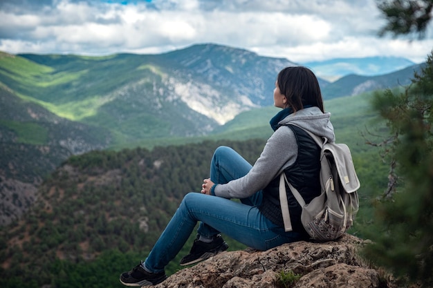 Mujer viajera joven en la cima del acantilado de la montaña