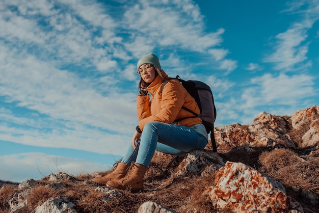 Mujer viajera de la libertad sentada en la cima de las montañas y disfrutando de una naturaleza maravillosa. Chica joven en la cima de la montaña con una vista perfecta de las montañas nevadas. concepto de viaje