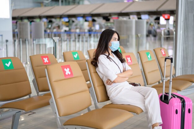 Una mujer viajera lleva una máscara protectora en el aeropuerto internacional, viaja bajo la pandemia de Covid-19, viajes de seguridad, protocolo de distanciamiento social, nuevo concepto de viaje normal.