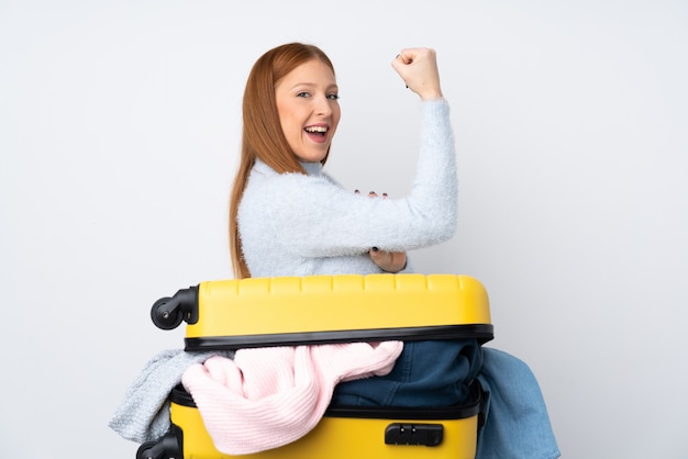 Mujer viajera con una maleta llena de ropa haciendo un gesto fuerte
