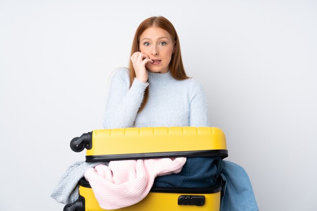 Mujer viajera con una maleta llena de ropa nerviosa y asustada