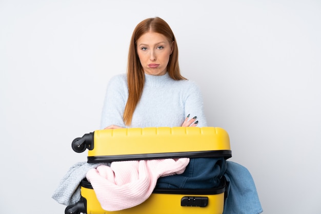 Mujer viajera con una maleta llena de ropa triste