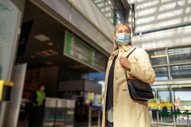 Mujer viajera con máscara de seguridad médica mientras espera el vuelo durante la pandemia
