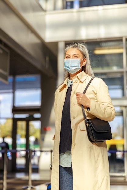 Mujer viajera con mascarilla protectora mientras espera el vuelo durante la pandemia