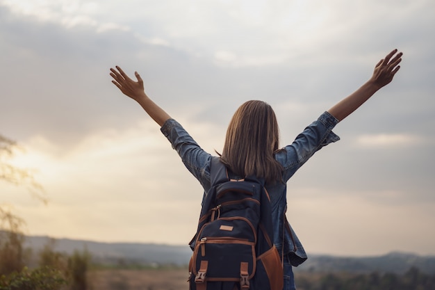 Mujer viajera con mochila con brazos levantados.