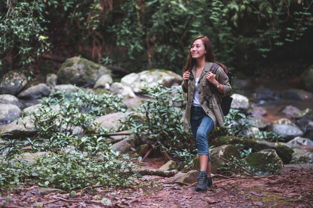 Una mujer viajera con mochila caminando por el bosque.