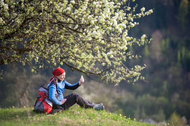 Mujer viajera con una mochila cerca de un árbol en flor.