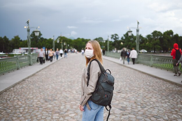 Mujer viajera con mochila y mascarilla médica