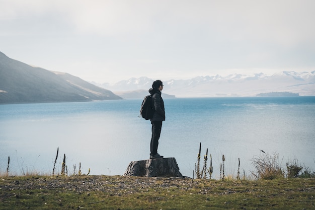 Mujer viajera de pie junto al lago.