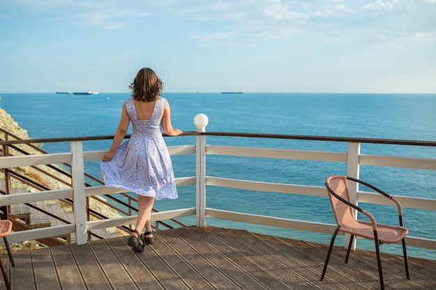 Mujer viajera relajándose y mirando al mar.