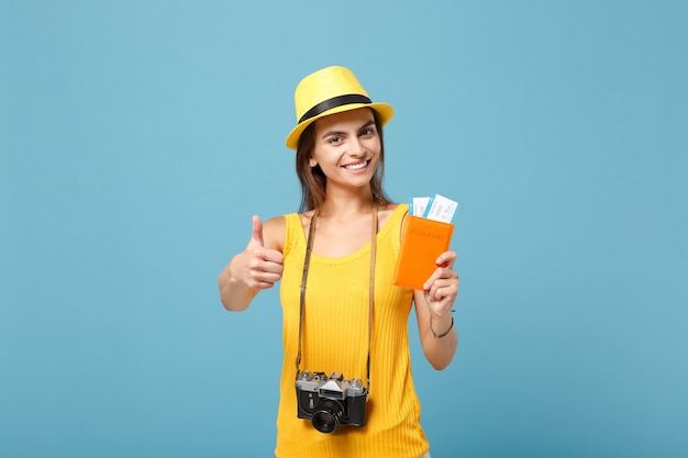 Mujer viajera en ropa casual de verano amarillo y sombrero con cámara de boletos en azul