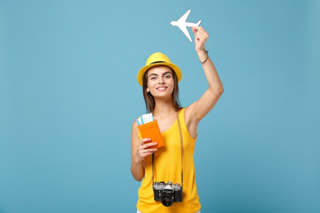 Mujer viajera en ropa casual de verano amarillo y sombrero con cámara de boletos en azul