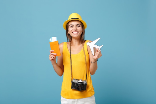 Mujer viajera en ropa casual de verano amarillo y sombrero con cámara de boletos en azul