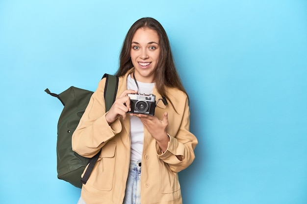 Mujer viajera tomando fotos con una cámara vintage en azul