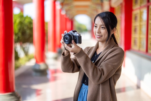 Una mujer viajera usa una cámara digital para tomar fotos en un templo chino