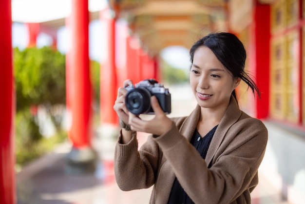 Una mujer viajera usa una cámara digital para tomar fotos en un templo chino