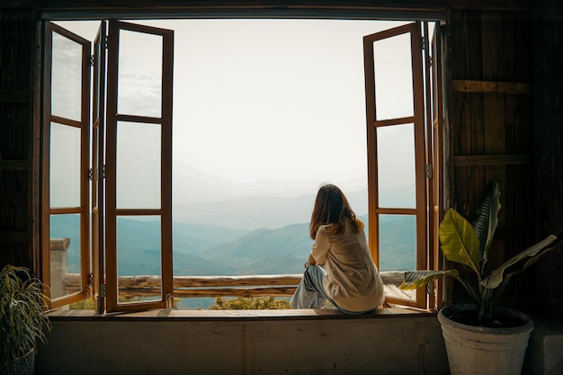 Mujer viajera en una ventana de madera mirando increíbles vistas a las montañas, concepto de viaje de pasión por los viajes.