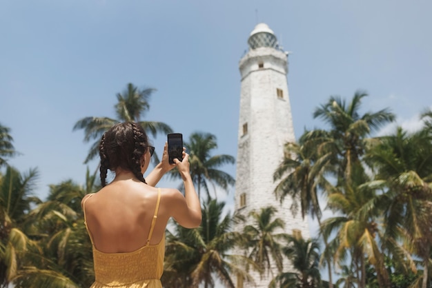 Mujer viajera vestida frente al famoso punto de referencia del país de sri lanka tomando fotos en el teléfono inteligente