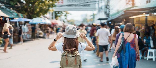 Foto mujer viajera de visita en bangkok turista con mochila y sombrero de turismo en el mercado de fin de semana de chatuchak, punto de referencia y atracciones populares en bangkok tailandia viajes en el concepto del sudeste asiático