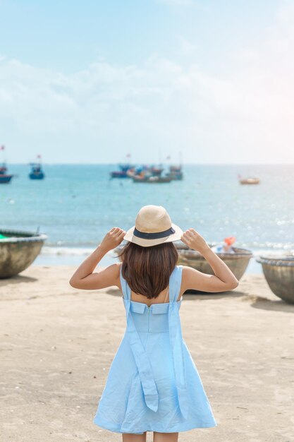 Mujer viajera visitando la playa de My Khe y haciendo turismo en botes de acabado Turista con vestido azul y sombrero viajando en la ciudad de Da Nang Concepto de viaje de Vietnam y el sudeste asiático