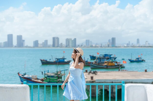 Mujer viajera visitando el puerto deportivo de Son Tra Turista con vestido azul y sombrero viajando en la ciudad de Da Nang Vietnam y el concepto de viaje del sudeste asiático