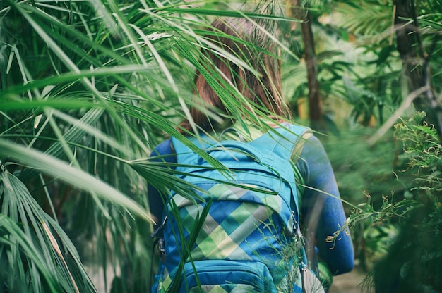 Mujer viajero con mochila caminando por sendero en el bosque tropical