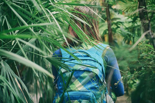 Mujer viajero con mochila caminando por sendero en el bosque tropical