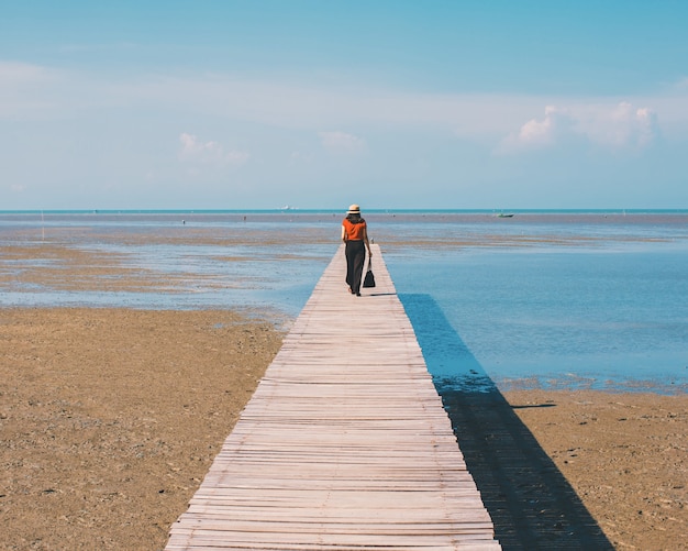 Mujer de viajero en el puente hacia el fondo del mar con filtro vintage