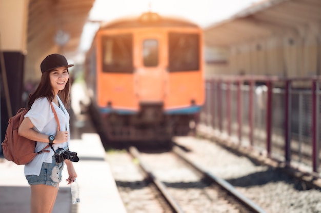 La mujer del viajero que camina y espera entrenan en la plataforma ferroviaria. Color del vintage