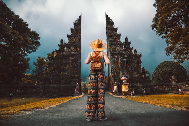 Mujer del viajero que presenta delante de un templo en Bali, Indonesia. Mujer con mochila en un viaje en Asia