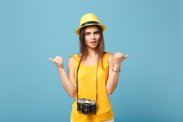 Mujer viajero en ropa casual de verano amarillo y sombrero con cámara de fotos en azul