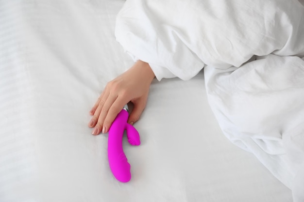 Foto mujer con un vibrador en la cama