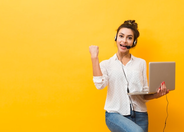 Foto mujer victoriosa con auriculares y sosteniendo portátil