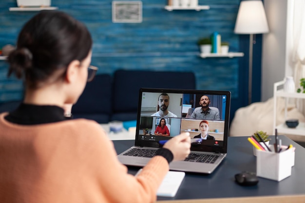 Mujer en una videollamada informativa con el equipo en la computadora portátil. freelancer trabajando desde la oficina en casa con una reunión grupal en línea en una computadora portátil. estudiante discutiendo con colegas en una conferencia de cámara web.