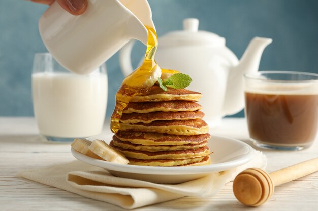 Mujer vierta miel sobre panqueques. Desayuno dulce