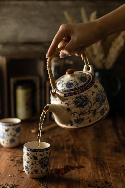 Una mujer vierte té en tazones de una tetera rusa tradicional Mesa de madera rústica