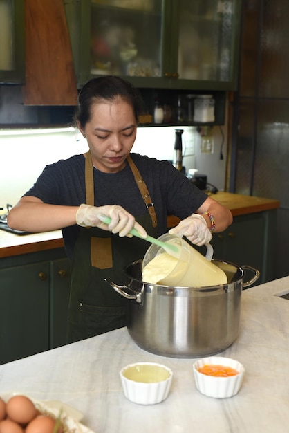 Mujer vietnamita mezclando masa para un pastel de queso casero