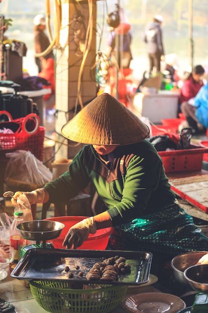 Mujer vietnamita que vende la comida en un mercado del borde de la carretera en Hoi An, provincia de Quang Nam, Vietnam.