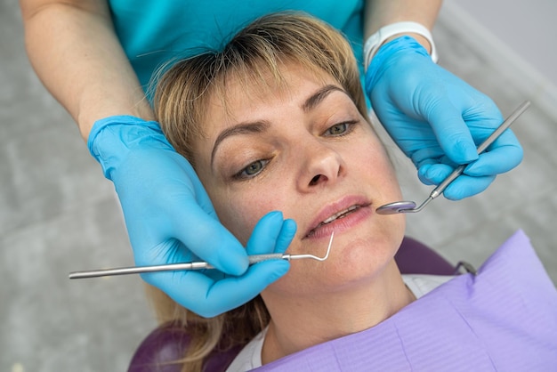 La mujer vino al dentista al propio dentista de la mujer para revisar los dientes en busca de caries.