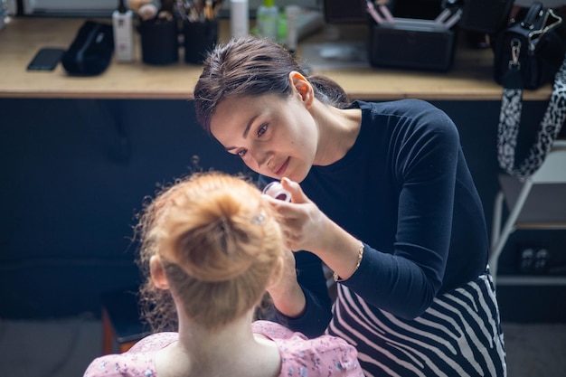 Mujer visagist aplicando cosmético de maquillaje a la mujer embarazada preparándose maquilladora trabajando