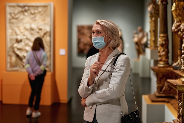 Mujer visitando el museo con una máscara antivirus