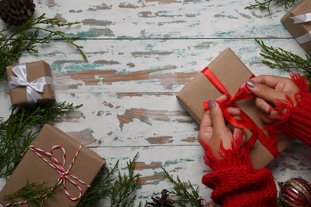 Mujer de vista aérea en suéter rojo envolver regalos de Navidad sobre un fondo de madera.