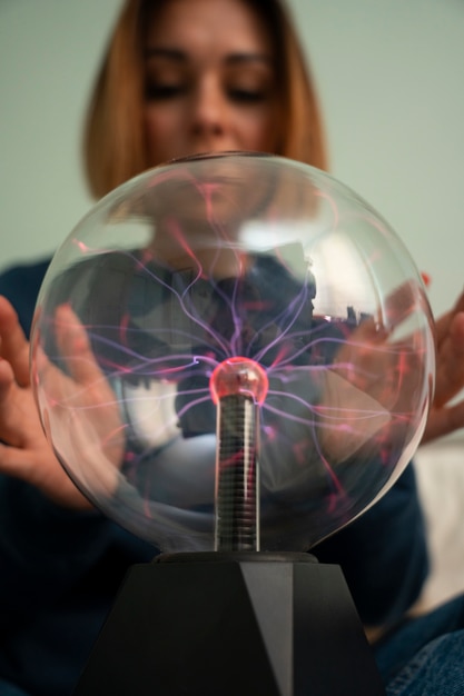 Foto mujer de vista frontal interactuando con una bola de plasma