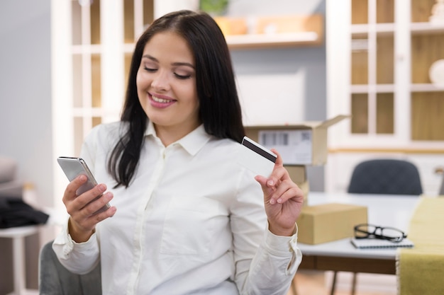 Foto mujer de vista frontal mirando a través de su teléfono para una nueva compra