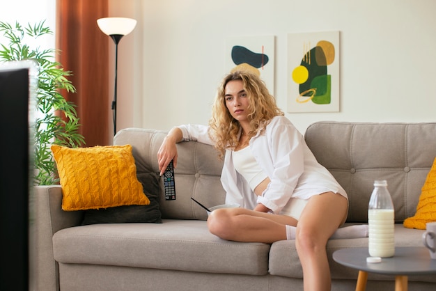 Foto mujer de vista lateral en el sofá viendo la televisión